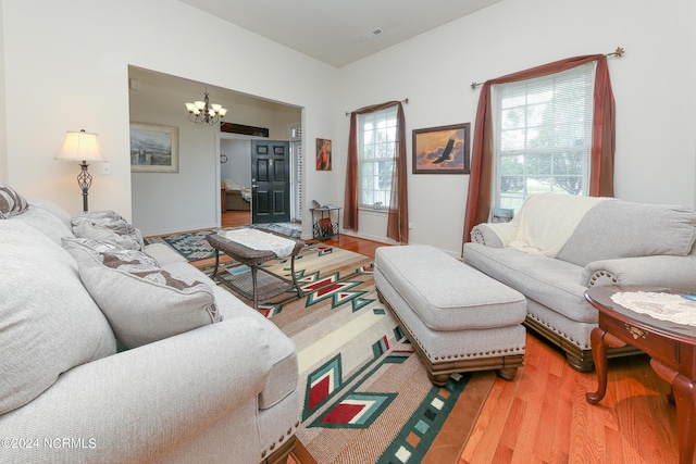 living area with wood finished floors, visible vents, and an inviting chandelier