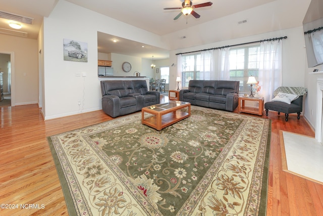 living room featuring baseboards, visible vents, ceiling fan, and wood finished floors