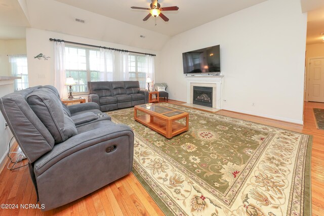 living room with ceiling fan, wood-type flooring, and vaulted ceiling