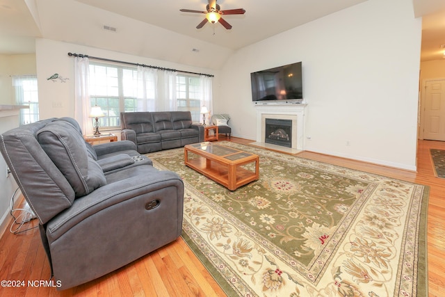 living area featuring lofted ceiling, a fireplace, visible vents, and wood finished floors