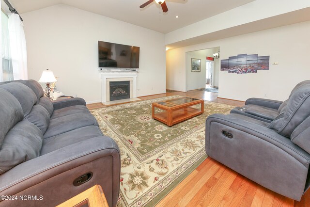 living room with hardwood / wood-style flooring, ceiling fan, and vaulted ceiling