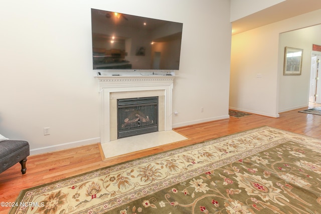 living area featuring a fireplace with flush hearth, wood finished floors, and baseboards