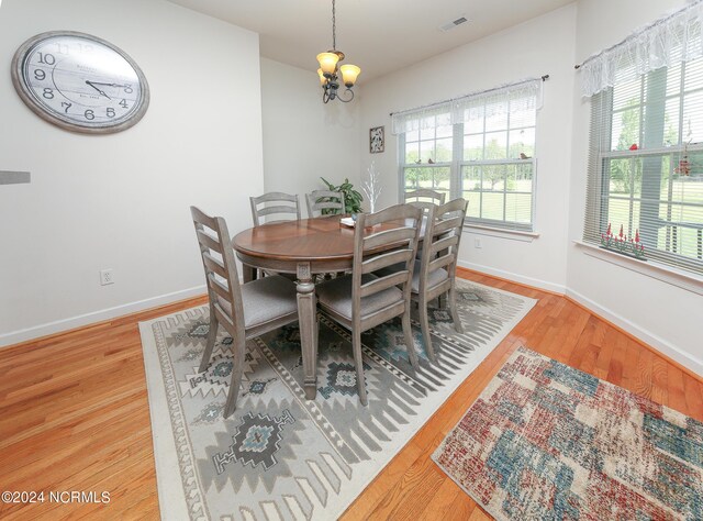 dining room with baseboards, wood finished floors, visible vents, and an inviting chandelier