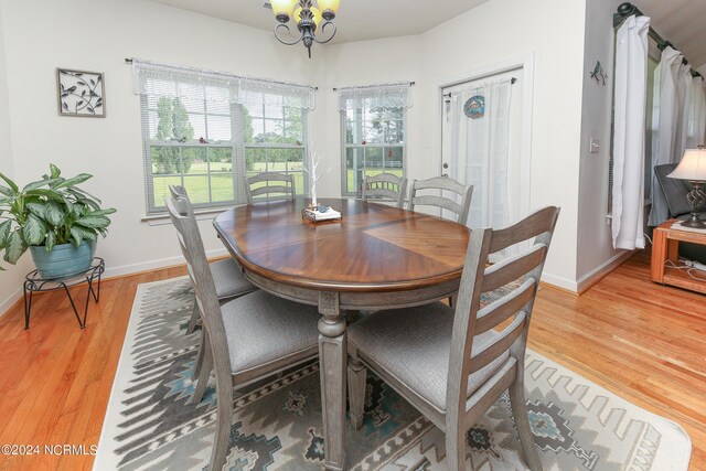 dining area with hardwood / wood-style floors and an inviting chandelier