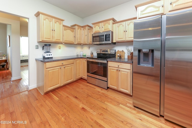 kitchen with light wood-type flooring, baseboards, stainless steel appliances, and light brown cabinetry