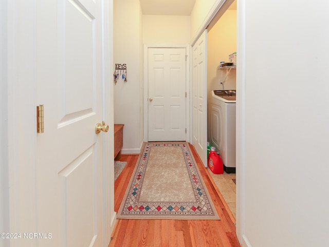 doorway featuring washer / clothes dryer, baseboards, and light wood finished floors