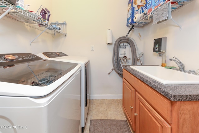 laundry room featuring light tile patterned floors, a sink, baseboards, cabinet space, and washing machine and clothes dryer