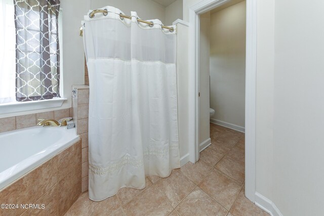 bathroom with a relaxing tiled tub and toilet