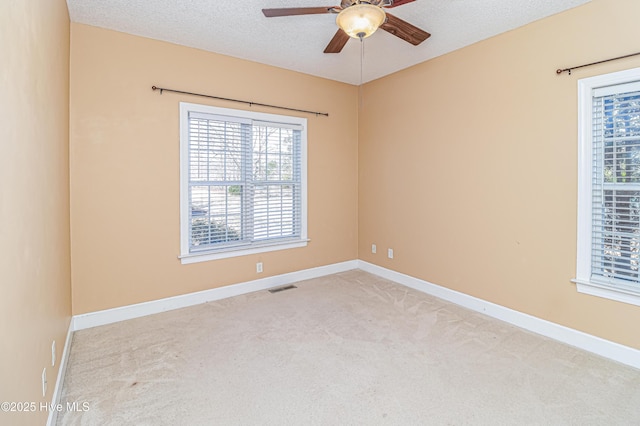 unfurnished room with a textured ceiling, ceiling fan, and light carpet