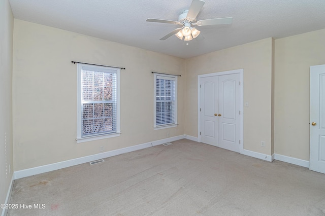 unfurnished bedroom featuring ceiling fan, light colored carpet, and a textured ceiling