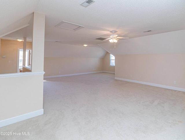 interior space featuring lofted ceiling, ceiling fan, light colored carpet, and a textured ceiling