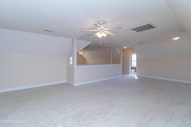 additional living space with vaulted ceiling, ceiling fan, light colored carpet, and a textured ceiling