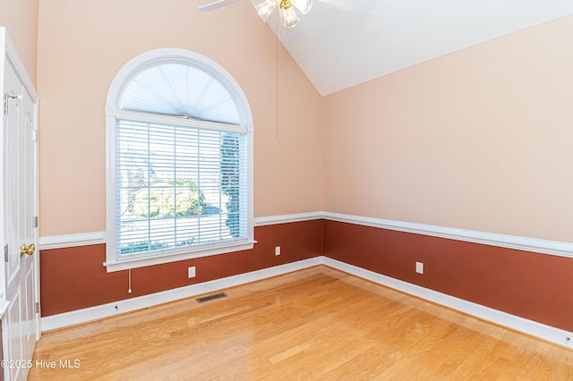 spare room with hardwood / wood-style floors, high vaulted ceiling, and ceiling fan