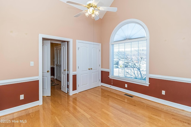 unfurnished bedroom featuring a closet, light hardwood / wood-style floors, high vaulted ceiling, and ceiling fan