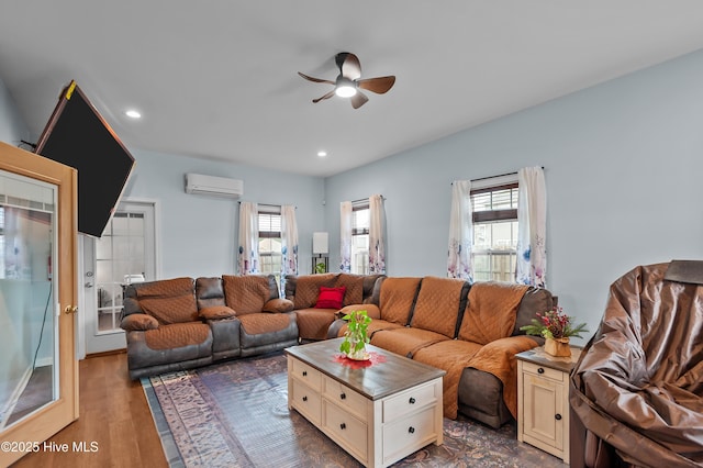 living room featuring hardwood / wood-style floors, a wall unit AC, a healthy amount of sunlight, and ceiling fan