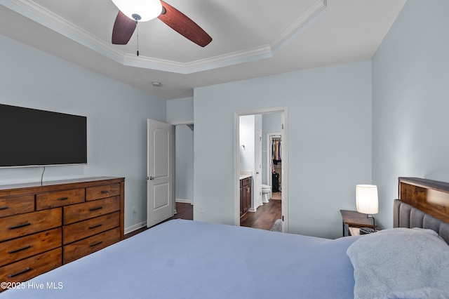 bedroom featuring crown molding, ensuite bath, ceiling fan, dark hardwood / wood-style floors, and a raised ceiling