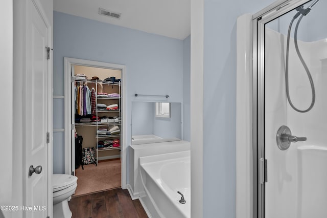 bathroom featuring wood-type flooring, shower with separate bathtub, and toilet