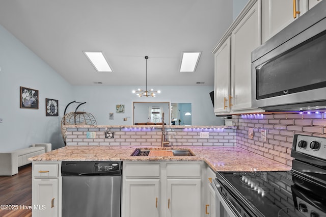 kitchen with sink, white cabinetry, stainless steel appliances, tasteful backsplash, and light stone countertops