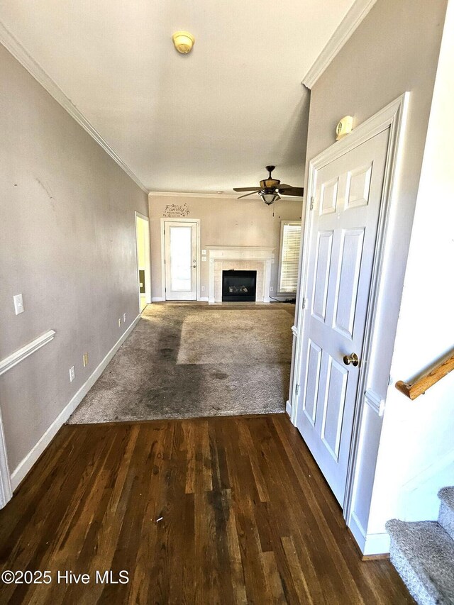 unfurnished living room featuring ceiling fan, dark hardwood / wood-style flooring, and crown molding