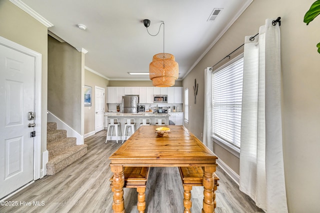 dining room with ornamental molding and light hardwood / wood-style floors