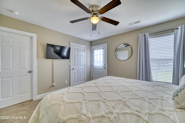 bedroom with two closets, light carpet, and ceiling fan