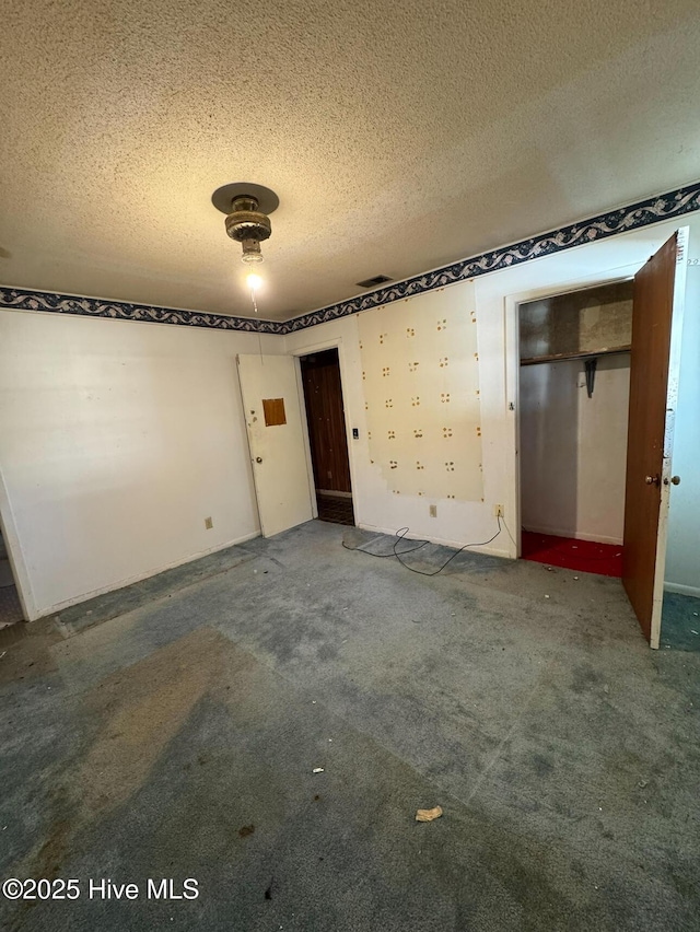 empty room with carpet floors and a textured ceiling