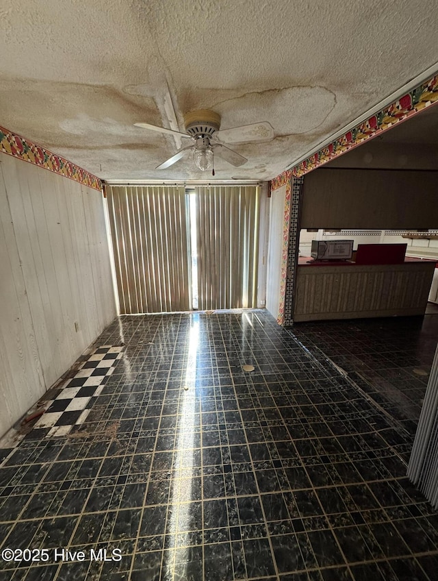 spare room featuring ceiling fan and wooden walls