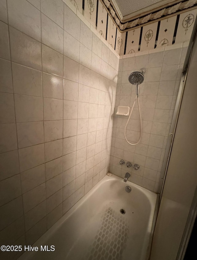 bathroom with tiled shower / bath and a textured ceiling