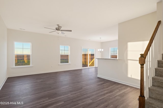 unfurnished living room featuring ceiling fan with notable chandelier and dark hardwood / wood-style flooring