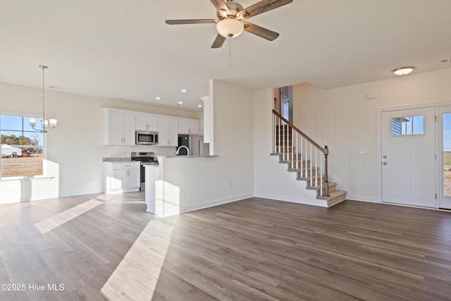 unfurnished living room with hardwood / wood-style floors and ceiling fan with notable chandelier