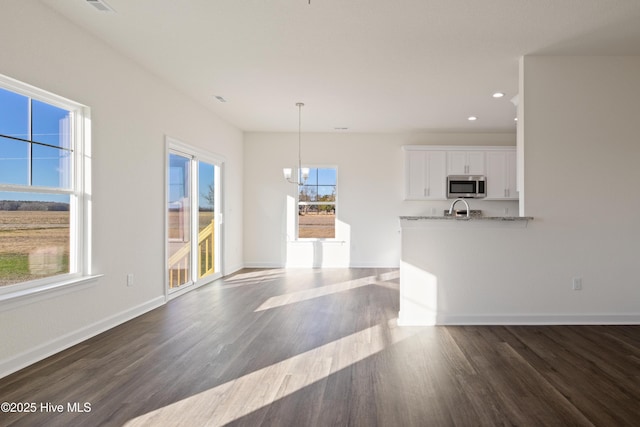 kitchen with hanging light fixtures, light stone countertops, plenty of natural light, white cabinetry, and a chandelier