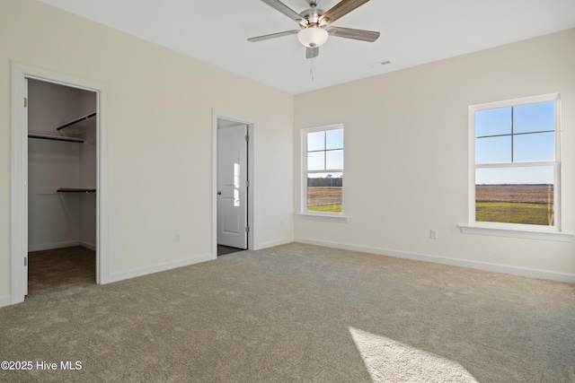 unfurnished bedroom featuring ceiling fan, light colored carpet, a spacious closet, and a closet