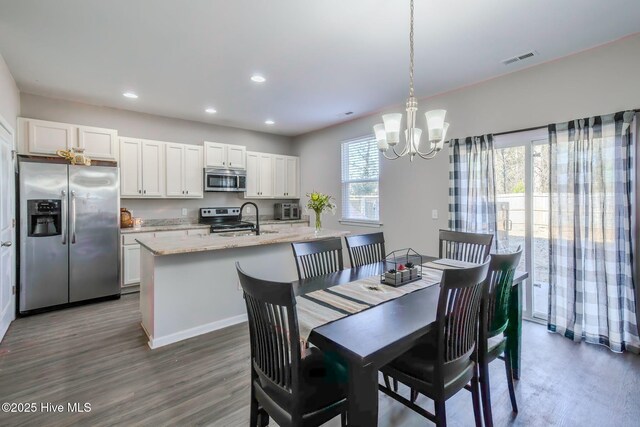 dining space with dark hardwood / wood-style floors, an inviting chandelier, a wealth of natural light, and sink