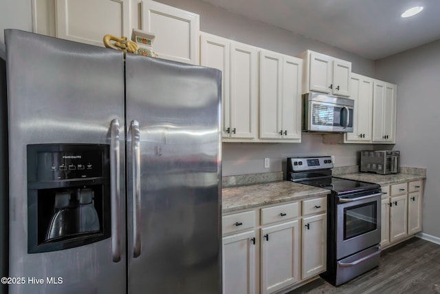 kitchen with light stone counters, white cabinets, stainless steel appliances, and dark hardwood / wood-style floors