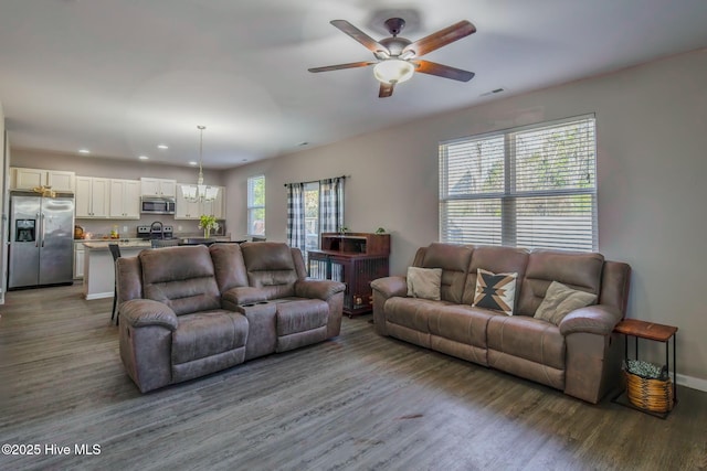 living room with hardwood / wood-style floors and ceiling fan with notable chandelier