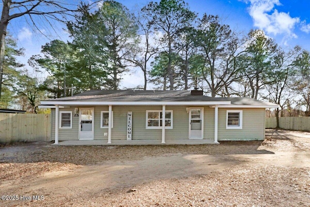 view of front of house with a porch, fence, and a chimney