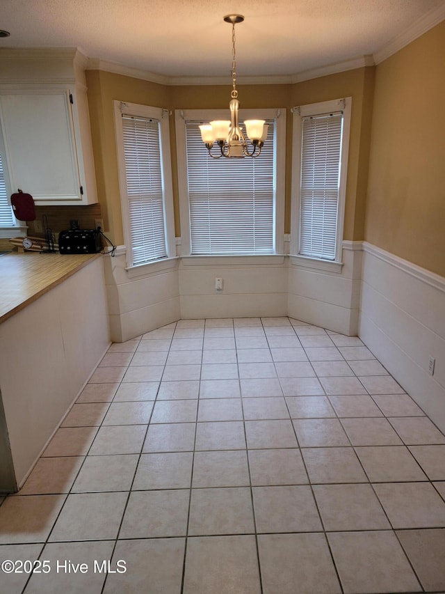 unfurnished dining area with a textured ceiling, a notable chandelier, light tile patterned floors, and ornamental molding