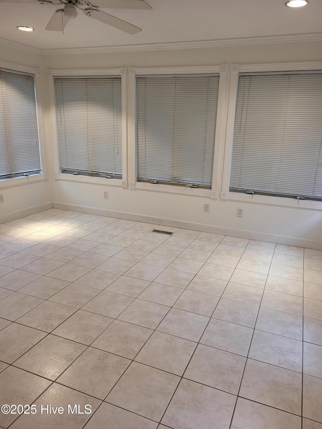 tiled empty room with ceiling fan and crown molding