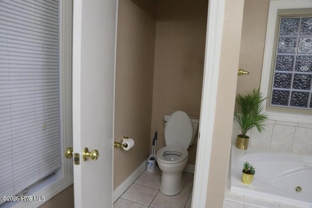 bathroom with tile patterned flooring, a relaxing tiled tub, and toilet