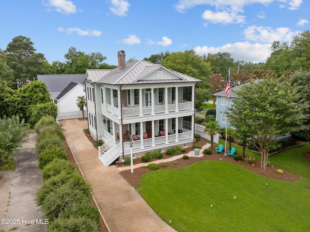 view of front facade featuring a front lawn, covered porch, a chimney, metal roof, and a standing seam roof