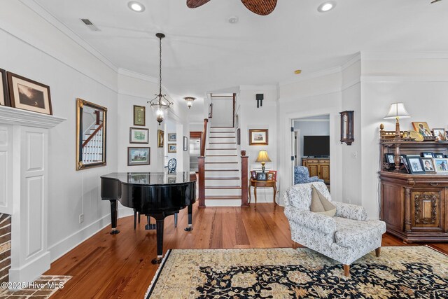 sitting room featuring light wood-type flooring, ceiling fan, and ornamental molding