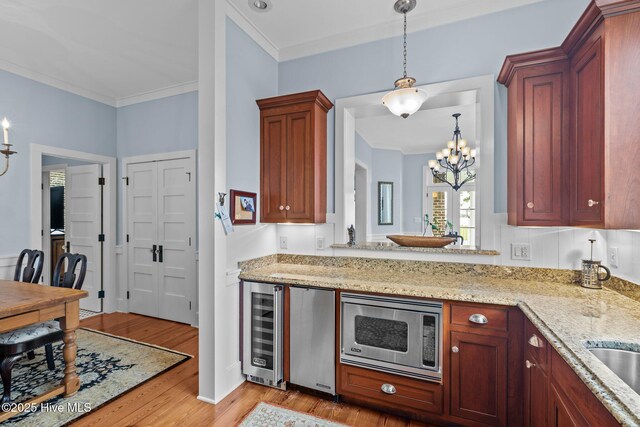 dining space with light wood-type flooring, ornamental molding, and an inviting chandelier