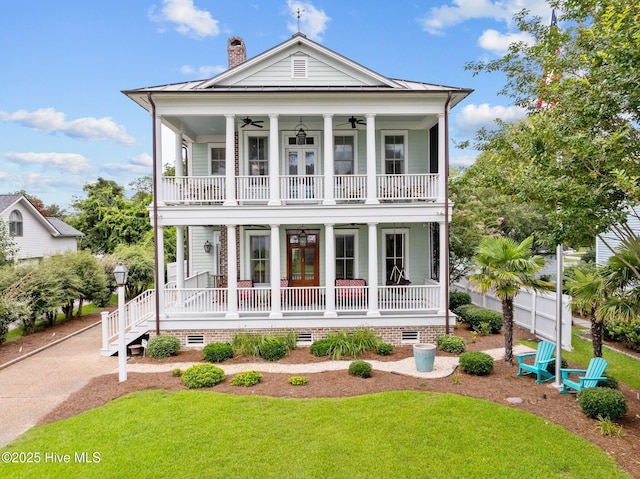 view of front of property featuring a front lawn, a standing seam roof, covered porch, a balcony, and ceiling fan