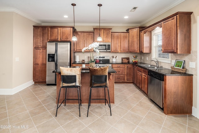 kitchen with ornamental molding, dark stone counters, stainless steel appliances, decorative light fixtures, and a center island