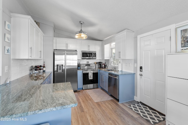 kitchen with pendant lighting, sink, a textured ceiling, white cabinetry, and stainless steel appliances