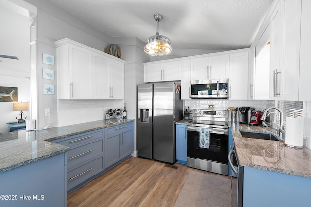 kitchen with pendant lighting, sink, tasteful backsplash, white cabinetry, and stainless steel appliances