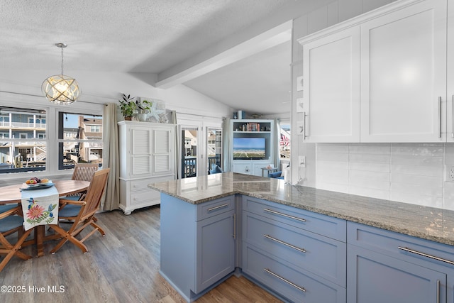 kitchen featuring white cabinetry, hardwood / wood-style floors, decorative light fixtures, and a textured ceiling