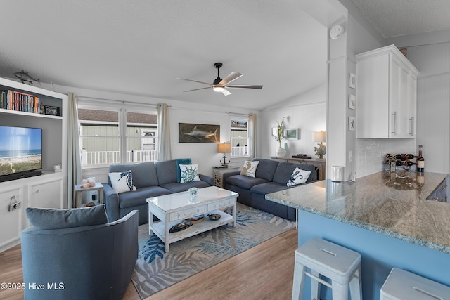 living room featuring ceiling fan, a healthy amount of sunlight, a textured ceiling, and light hardwood / wood-style flooring