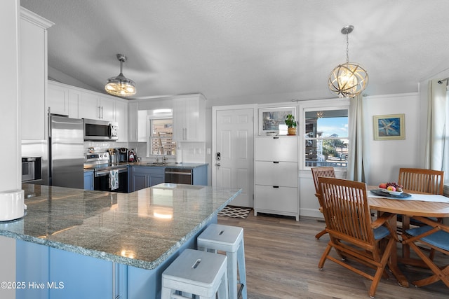 kitchen with white cabinets, appliances with stainless steel finishes, decorative light fixtures, and kitchen peninsula