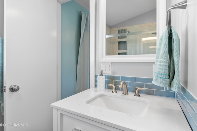 bathroom featuring decorative backsplash, vanity, vaulted ceiling, and an enclosed shower